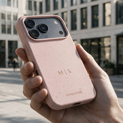 compoCASE Handyhülle in Soft Rose mit gravierten Initialen M|S in der Hand vor einer Stadtfassade