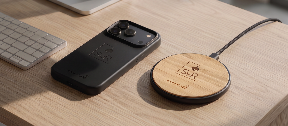 Kabellose Holz-Ladestation neben einem iPhone in schwarzer Hülle auf einem Schreibtisch